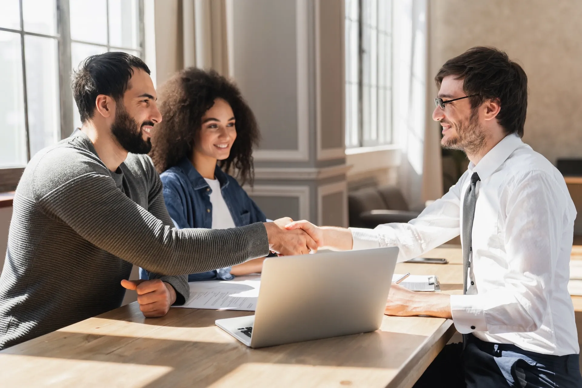 Man shaking hands with a couple in a business environment indicating new business setup services